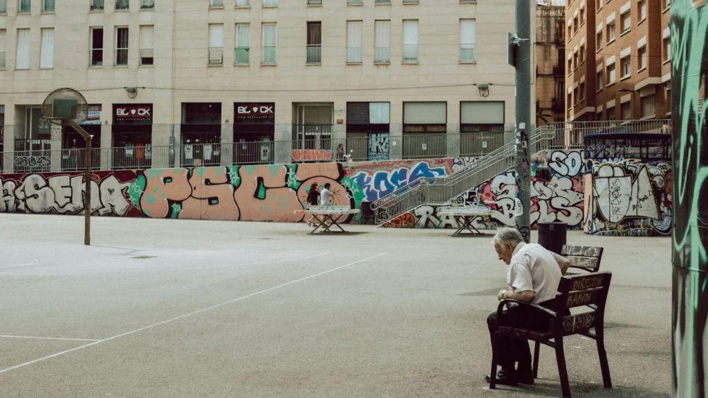 Пожилой человек сидит на скамейке в городе