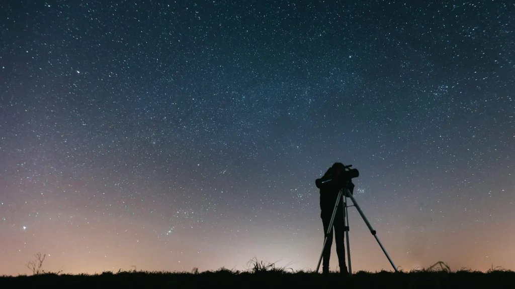 Человек смотрит в телескоп на ночное небо