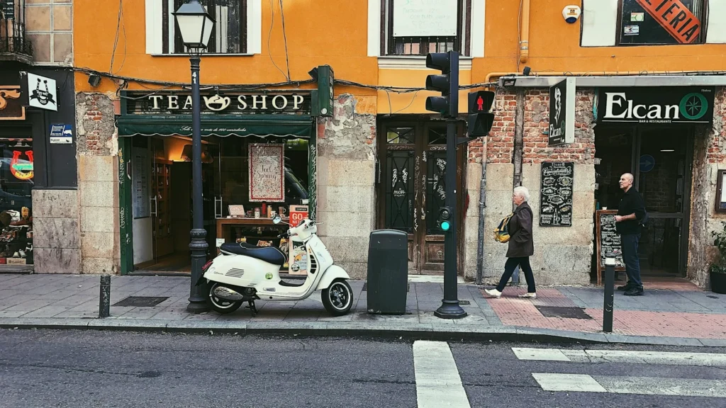 Женщина и мужчина идут мимо магазина чая; скутер