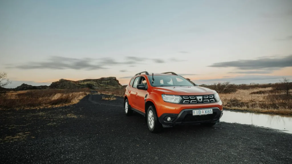 Оранжевый автомобиль Dacia на фоне гор