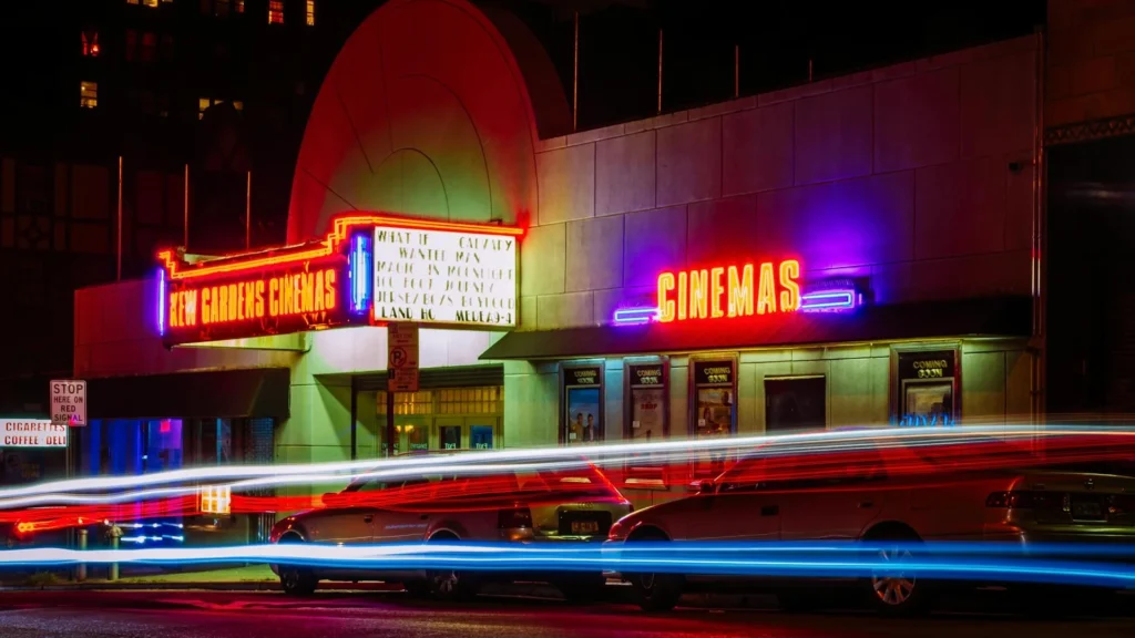 Здание кинотеатра с неоновыми вывесками ночью