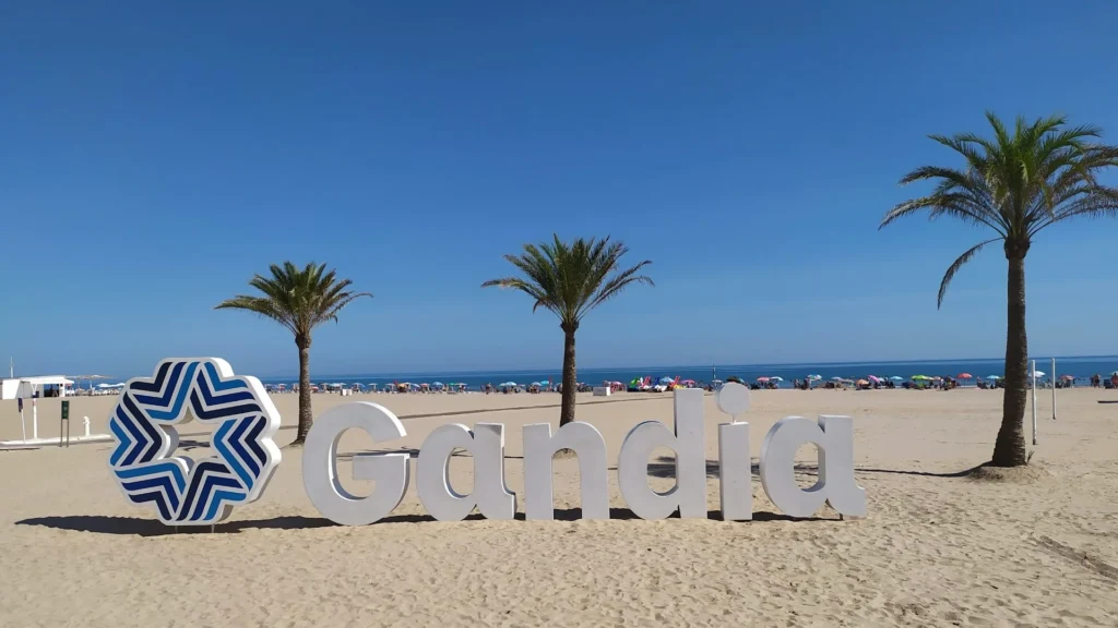 Слово Gandia на пляже на фоне пальм