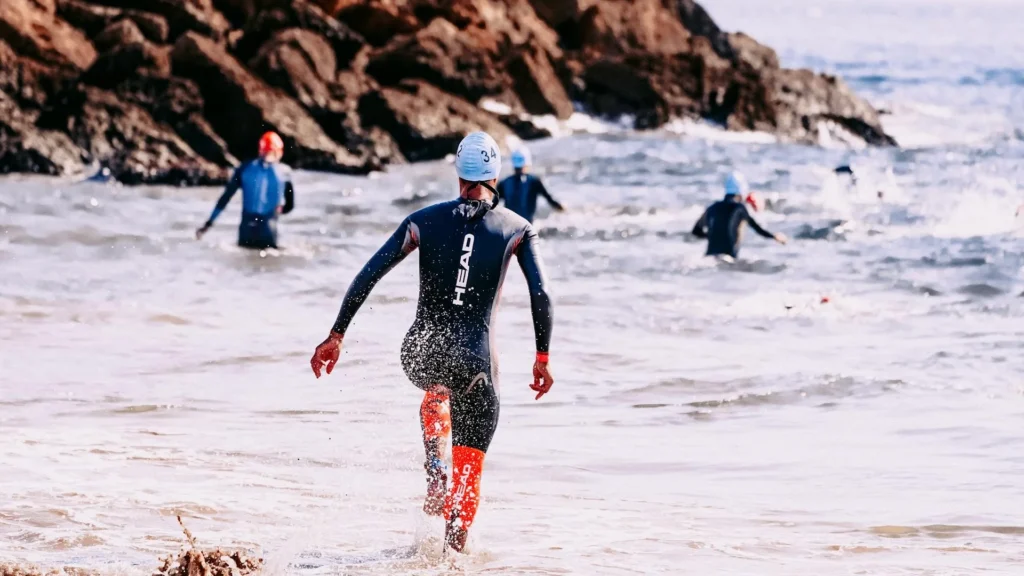 Спортсмены-пловцы забегают в море во время соревнований