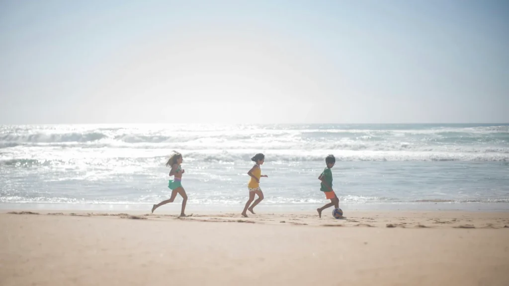 Дети бегут по морскому пляжу в солнечный день