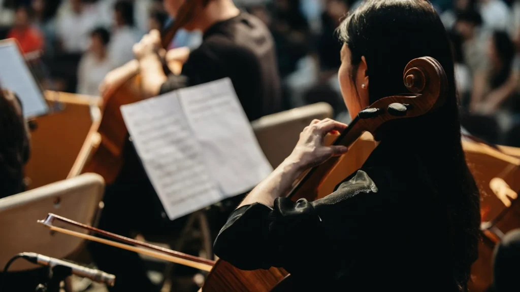 Девушка-музыкант играет в оркестре и смотрит на нотный стан