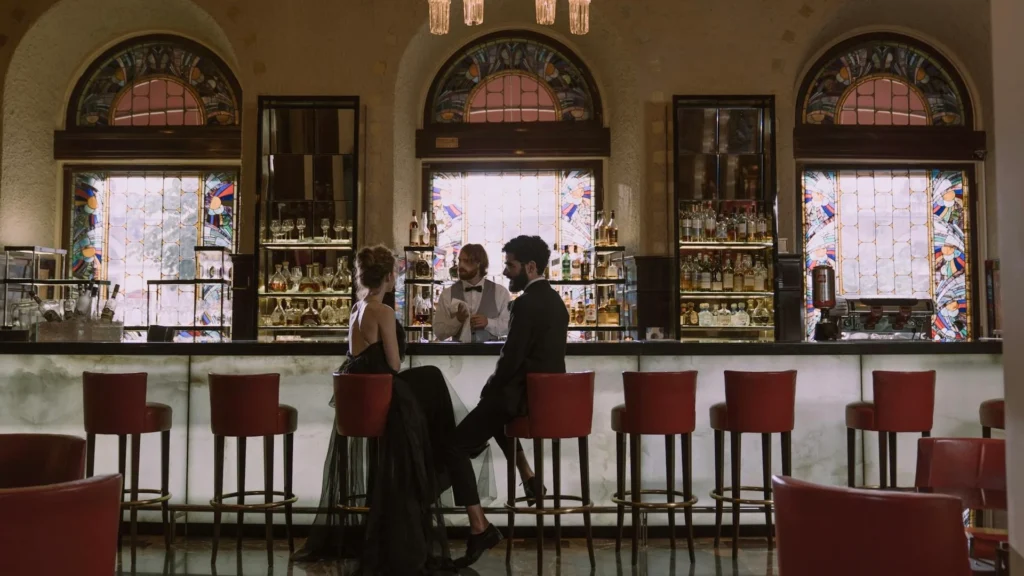 Пара в вечерних нарядах сидит за стойкой в историческом баре