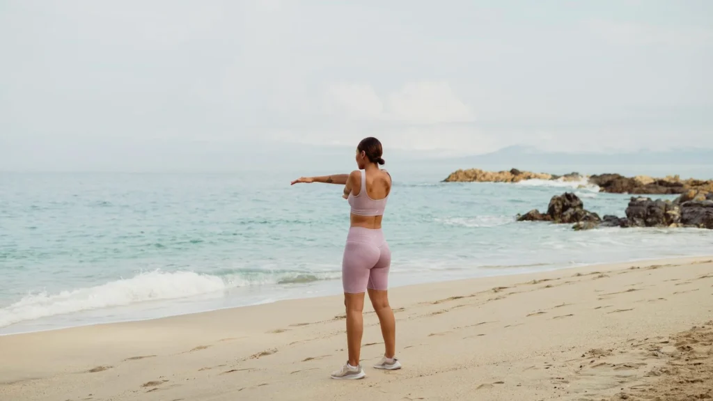 Спортивная девушка разминается на пляже