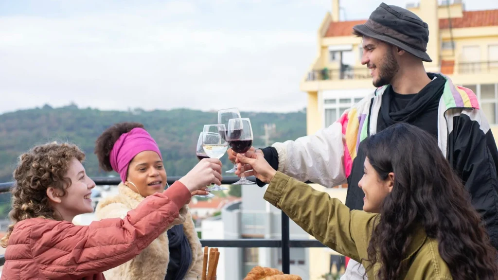 Компания друзей чокаются бокалами вина на террасе дома