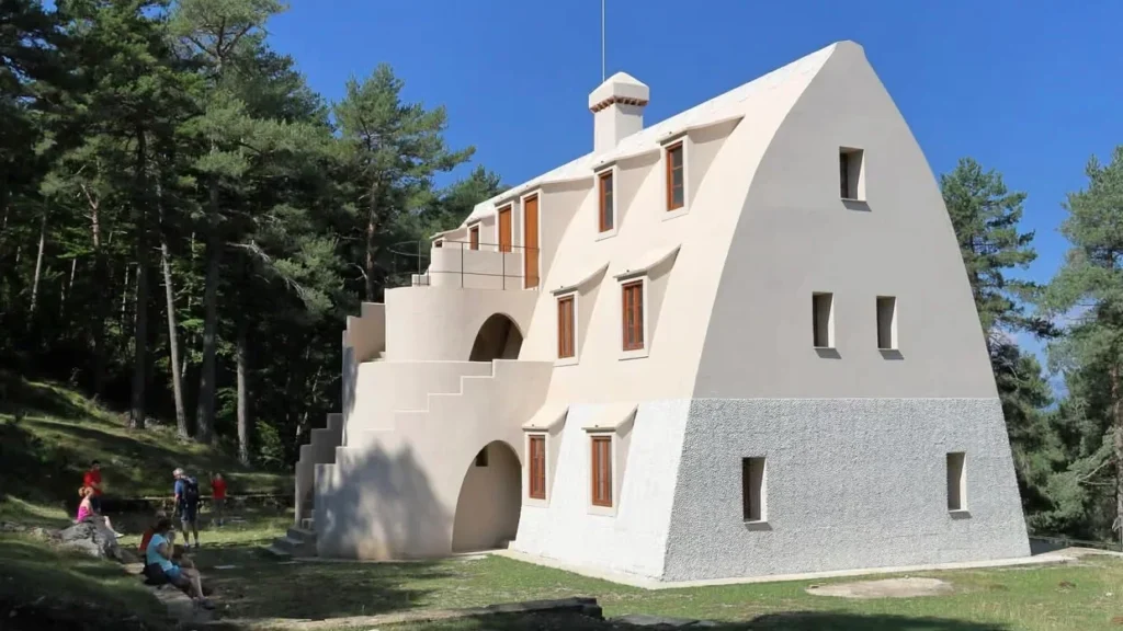 Белое шале нестандартной формы в лесу