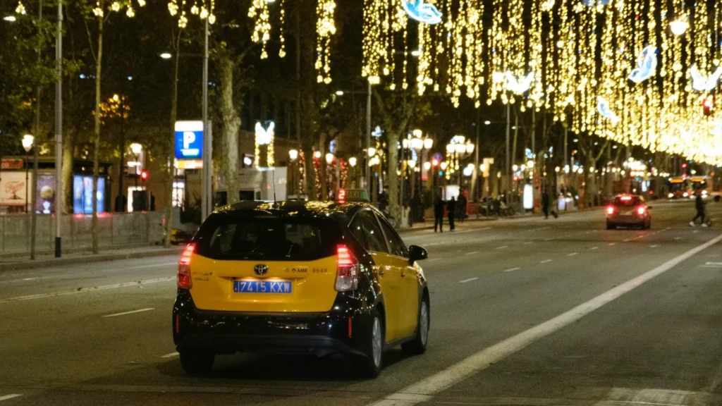 Желтое такси движется по улице, украшенной гирляндами