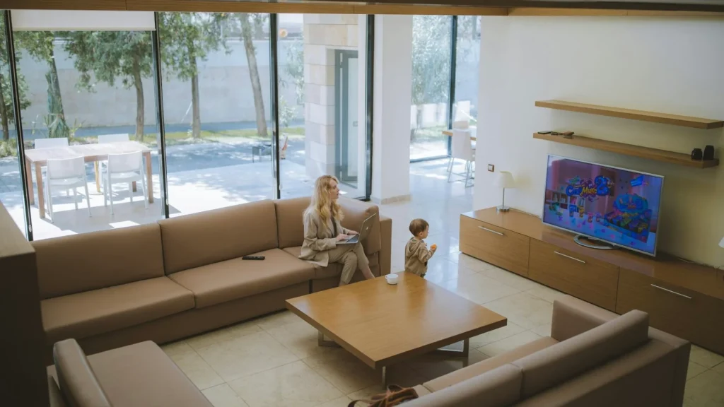 Молодая мать с ребенком смотрят телевизор в большом доме