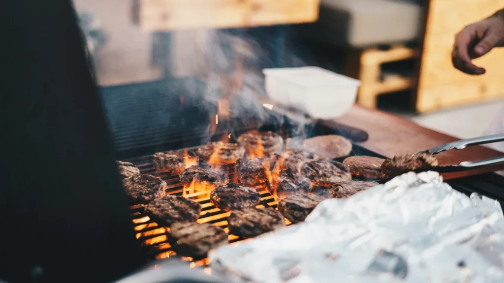 Человек готовит бургеры на гриле