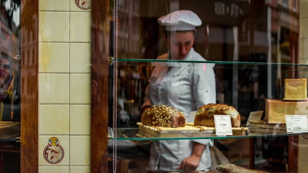 Девушка-пекарь смотрит на хлеб на витрине