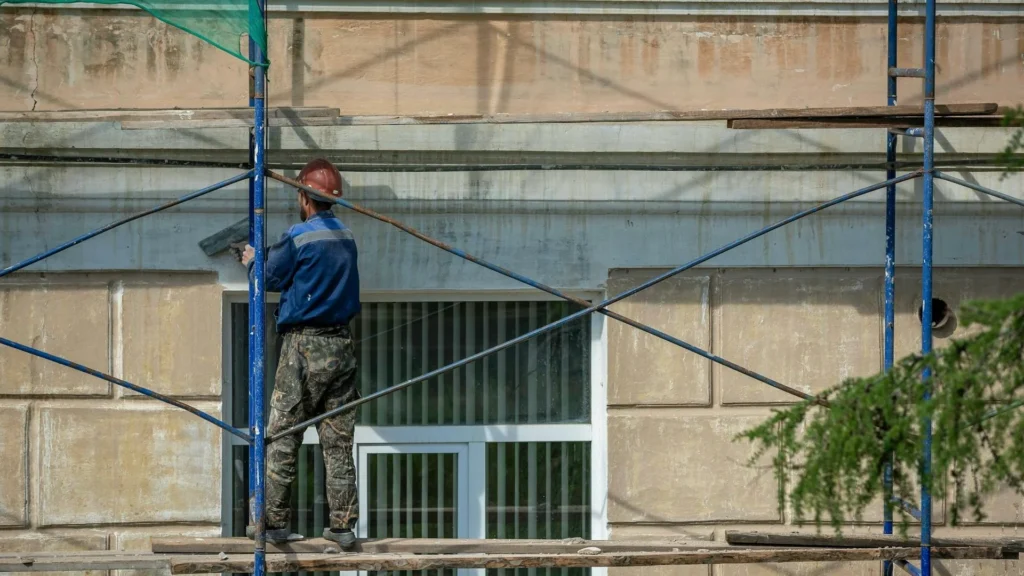 Рабочий ремонтирует фасад здания в Испании