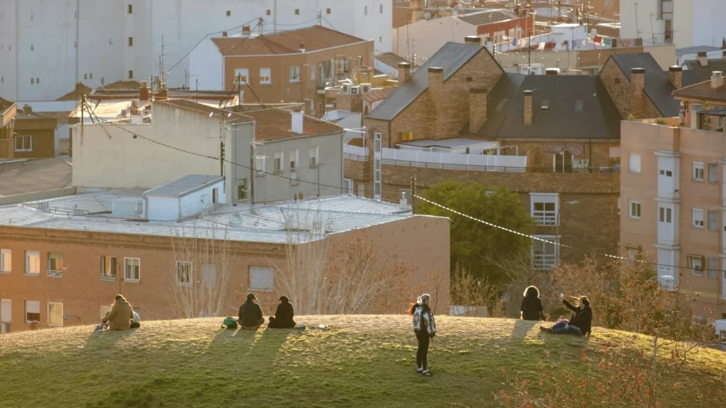 Люди отдыхают на газоне на фоне жилых домов