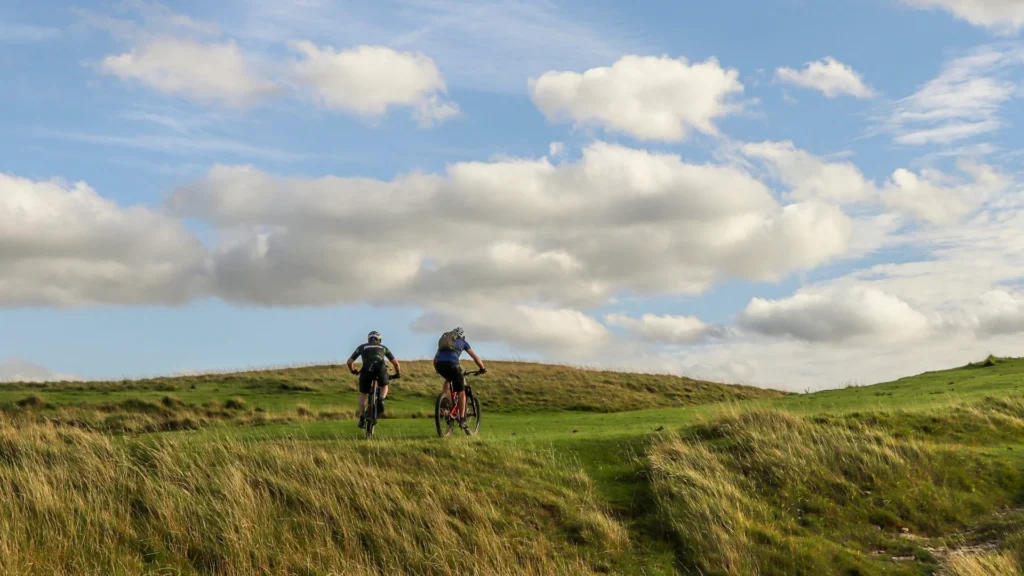 Два велосипедиста едут по зеленым холмам