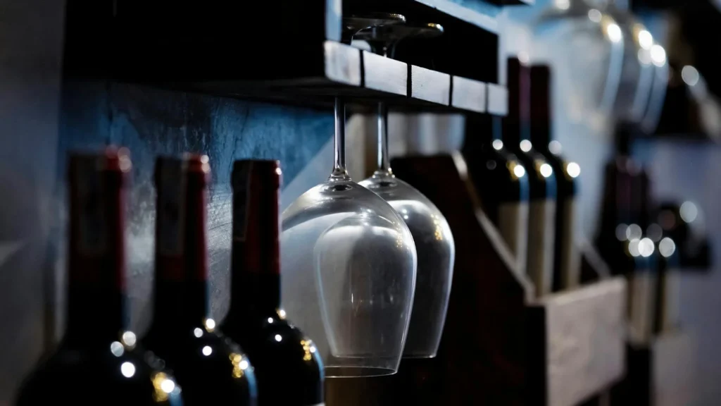 Бутылки вина и винные бокалы в темном баре