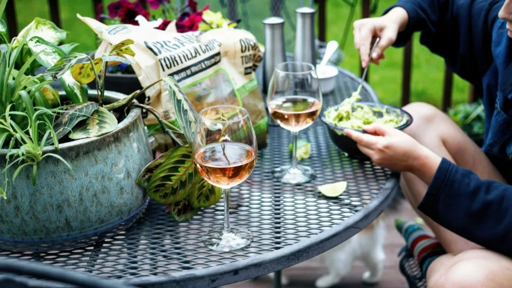 Женщина на террасе ест сала и пьет вино