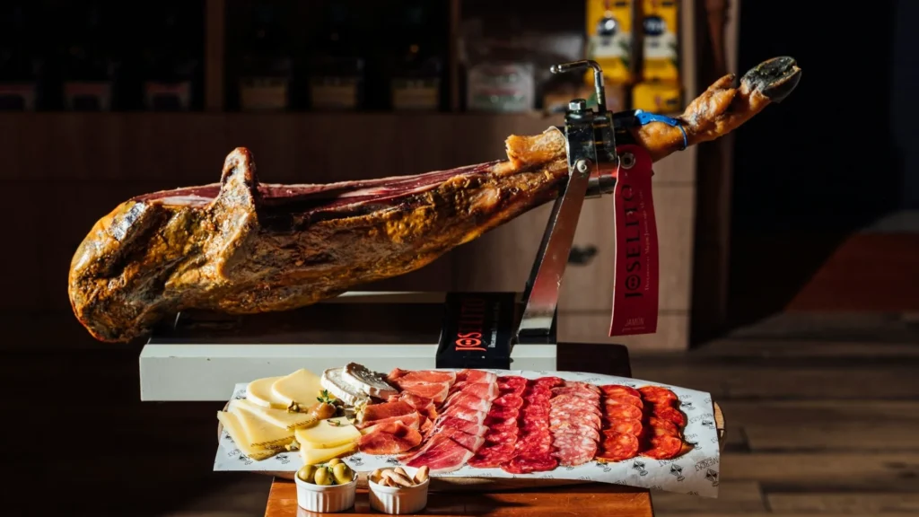 Окорок хамона на подставке, нарезка сырок и хамона на тарелке