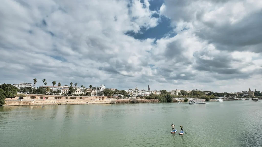 Река на фоне моста и города, люди на сапе