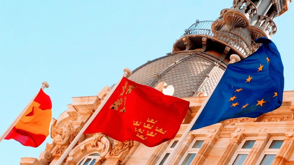 Флаги Испании, ЕС и региональный флаг на фоне исторического здания