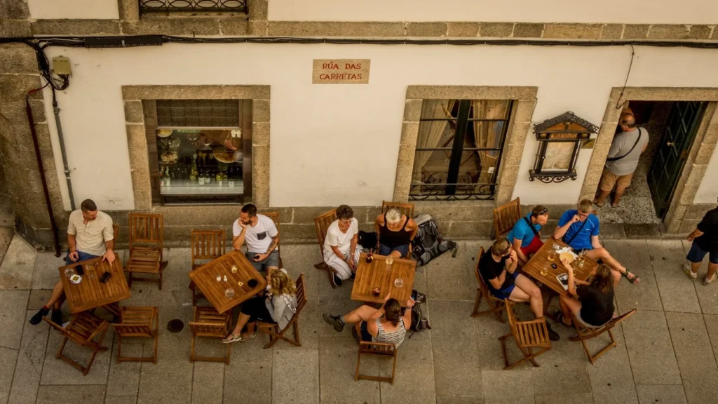 туристы сидят за столиками кафе на улице в испании