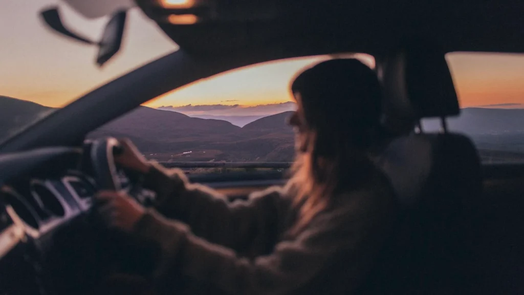 Женщина за рулем автомобиля на закате