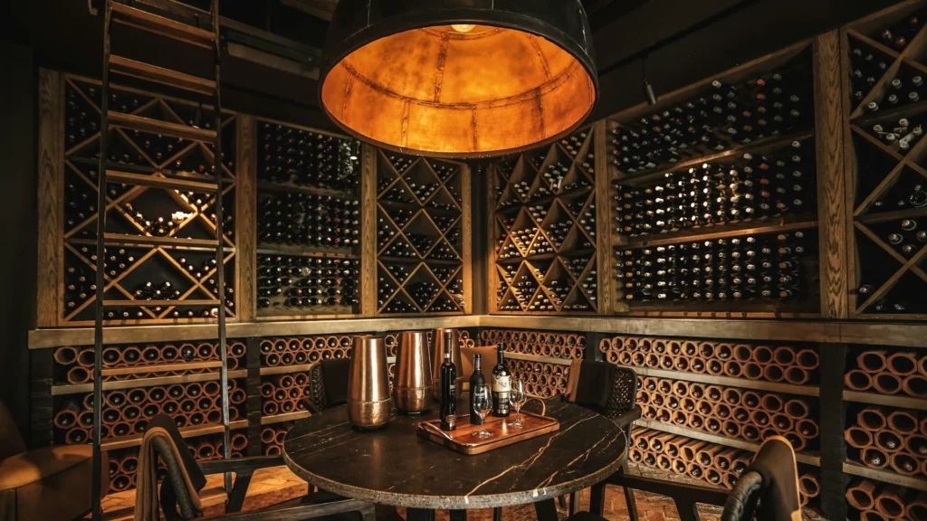 Винный погреб, стеллажи с кинными бутылками, стол с бокалами для вина