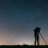 Человек смотрит в телескоп на ночное небо