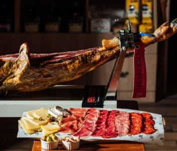 Окорок хамона на подставке, нарезка сырок и хамона на тарелке