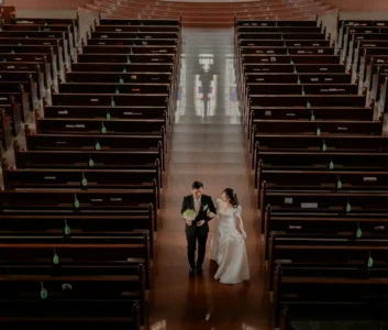 Пара молодоженов идет по проходу в церкви между скамейками