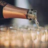 Бутылка шампанского, из которой разливают напиток по бокалам