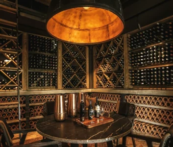 Винный погреб, стеллажи с кинными бутылками, стол с бокалами для вина