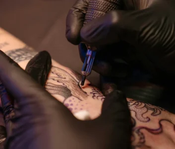 Тату-мастер делает татуировку на руке клиенту