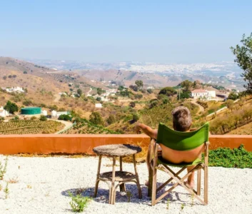 Мужчина в шезлонге на террасе смотрит на поля