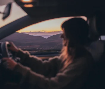 Женщина за рулем автомобиля на закате