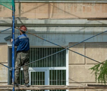 Рабочий ремонтирует фасад здания в Испании