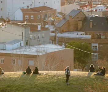 Люди отдыхают на газоне на фоне жилых домов