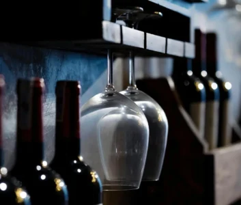 Бутылки вина и винные бокалы в темном баре